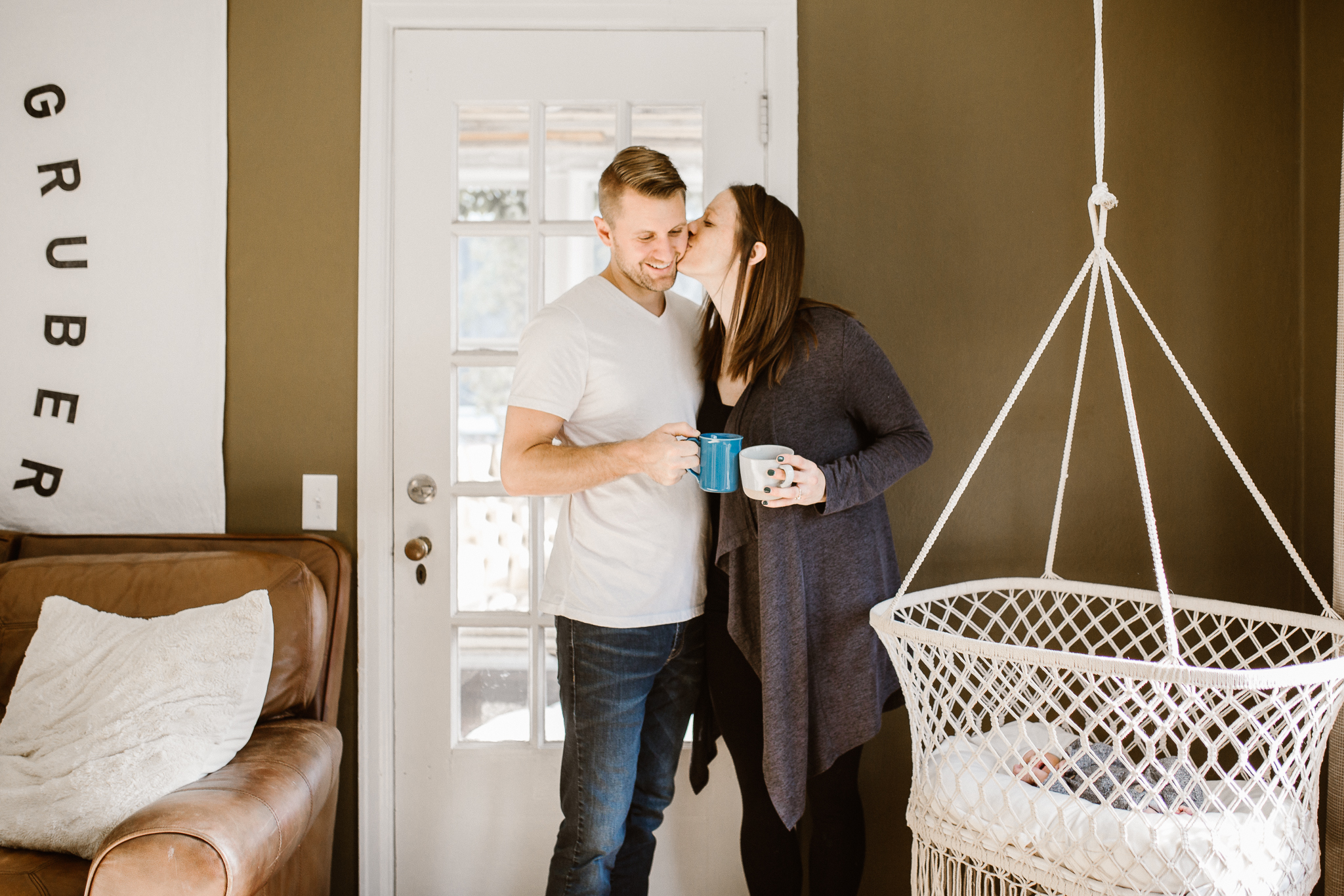 Couple kissing while looking at their newborn baby.